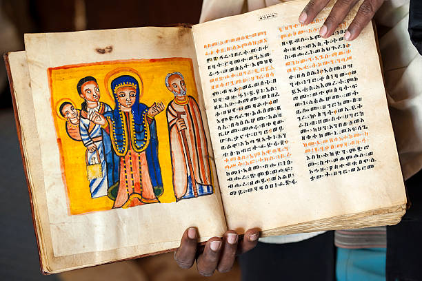 Priest is showing an ancient book in Ethiopia An old, handwritten and handpainted book (approx. 13th - 14th century). The book is written in the ancient language Geez, which is not used anymore except as liturgical language of the Ethiopian Orthodox Tewahedo Church.  ethiopian orthodox church stock pictures, royalty-free photos & images