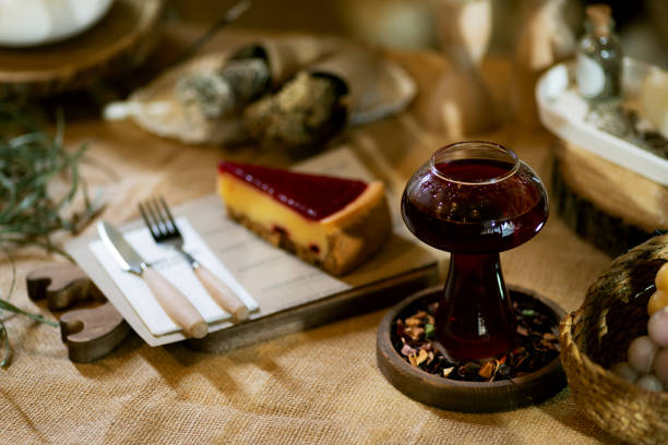 A warm scene showcasing a slice of strawberry cheesecake on a wooden board next to a cup of winter tea. Set on a burlap tablecloth under ambient candlelight, this setting embodies comfort and indulgence.