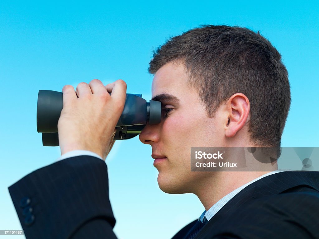 Joven mirando a través de un hombre de negocios aislado sobre cielo azul binocular - Foto de stock de Adulto libre de derechos