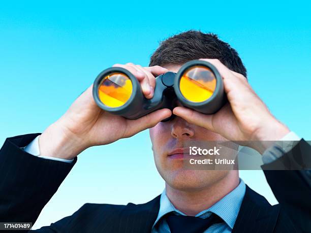 Joven Mirando A Través De Un Hombre De Negocios Aislado Sobre Cielo Azul Binocular Foto de stock y más banco de imágenes de Adulto