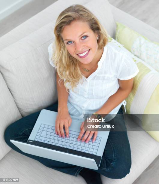 Junge Schöne Frau Sitzt Auf Einem Sofa Und Mit Einem Laptop Stockfoto und mehr Bilder von Attraktive Frau