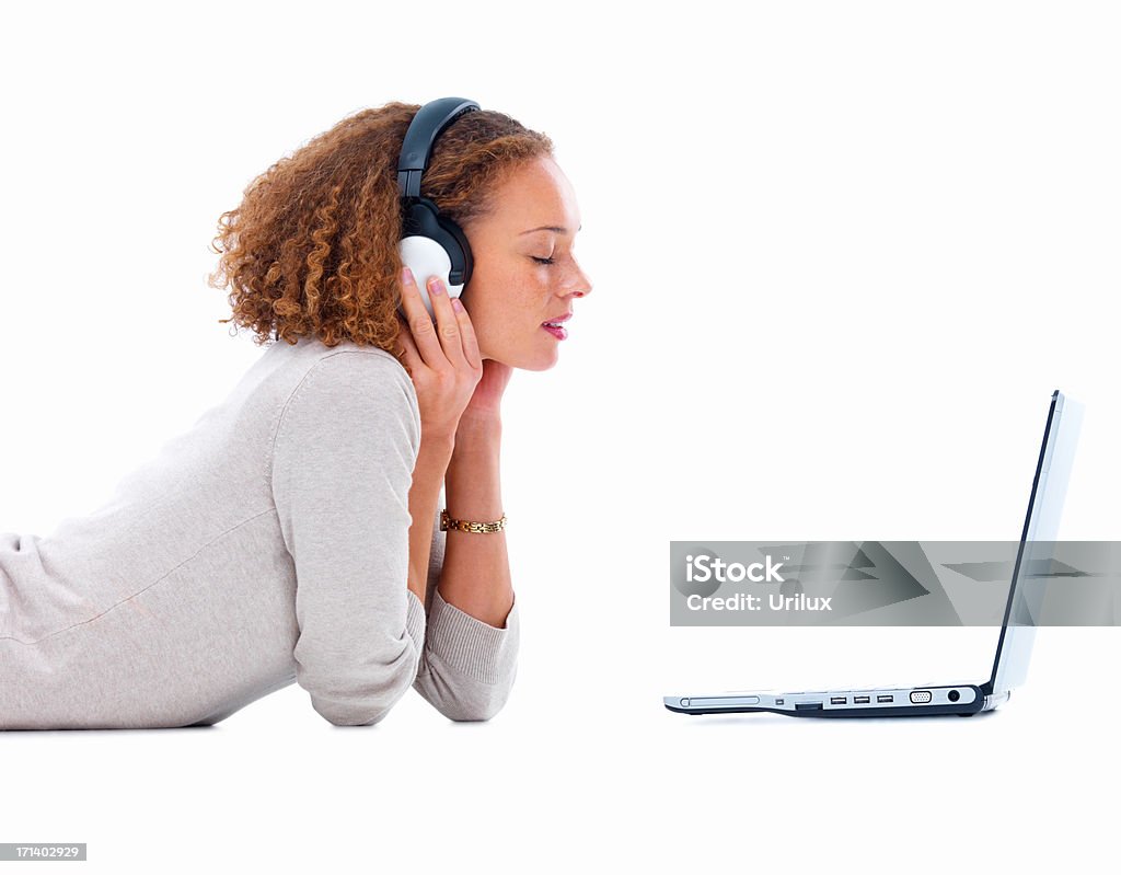 Vista lateral de uma jovem mulher com fones de ouvido e um laptop - Foto de stock de Figura para recortar royalty-free