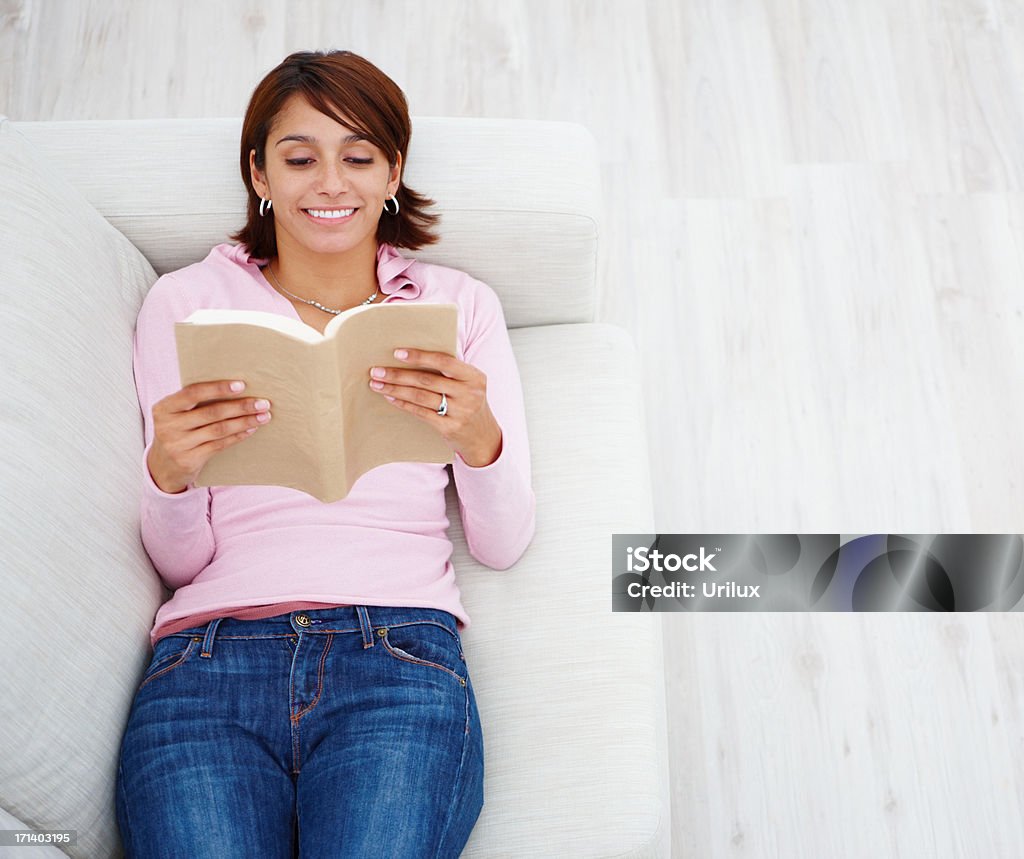 Jeune femme allongée sur le canapé et la lecture - Photo de Adulte libre de droits