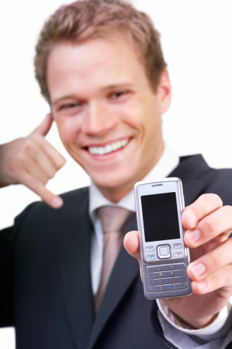 Happy businessman holding phone and smiling while standing on white studio background