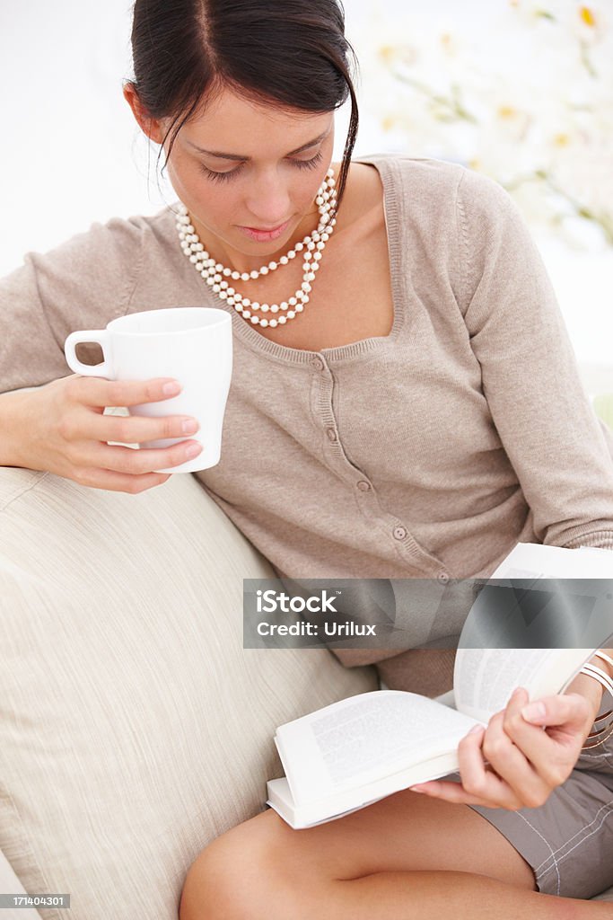 Jeune femme lisant livre avec tasse de thé à la main - Photo de Adulte libre de droits