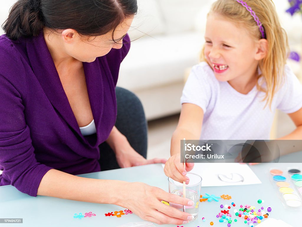 Szczęśliwa młoda matka siedzi z jej córka i rysowania - Zbiór zdjęć royalty-free (Biurko)