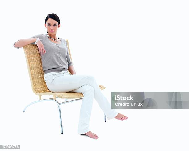 Young Woman Sitting On Chair Against Isolated White Background Stock Photo - Download Image Now