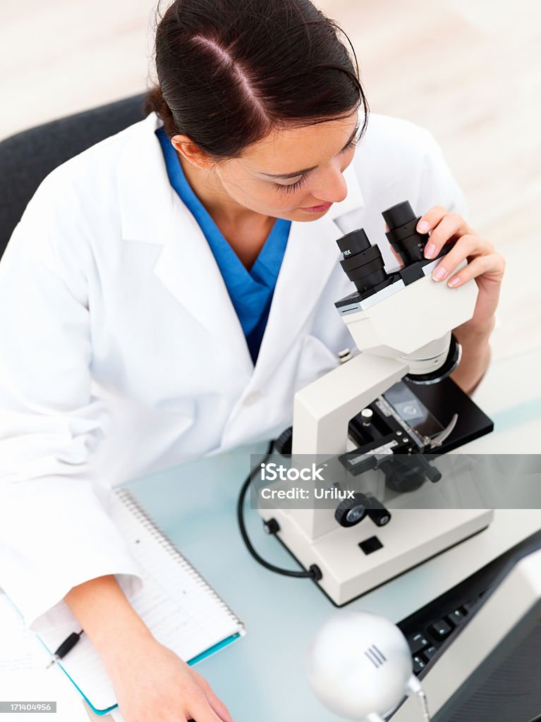 Исследователь, сидящая на стол с микроскопом - Стоковые фото Вертикальный роялти-фри