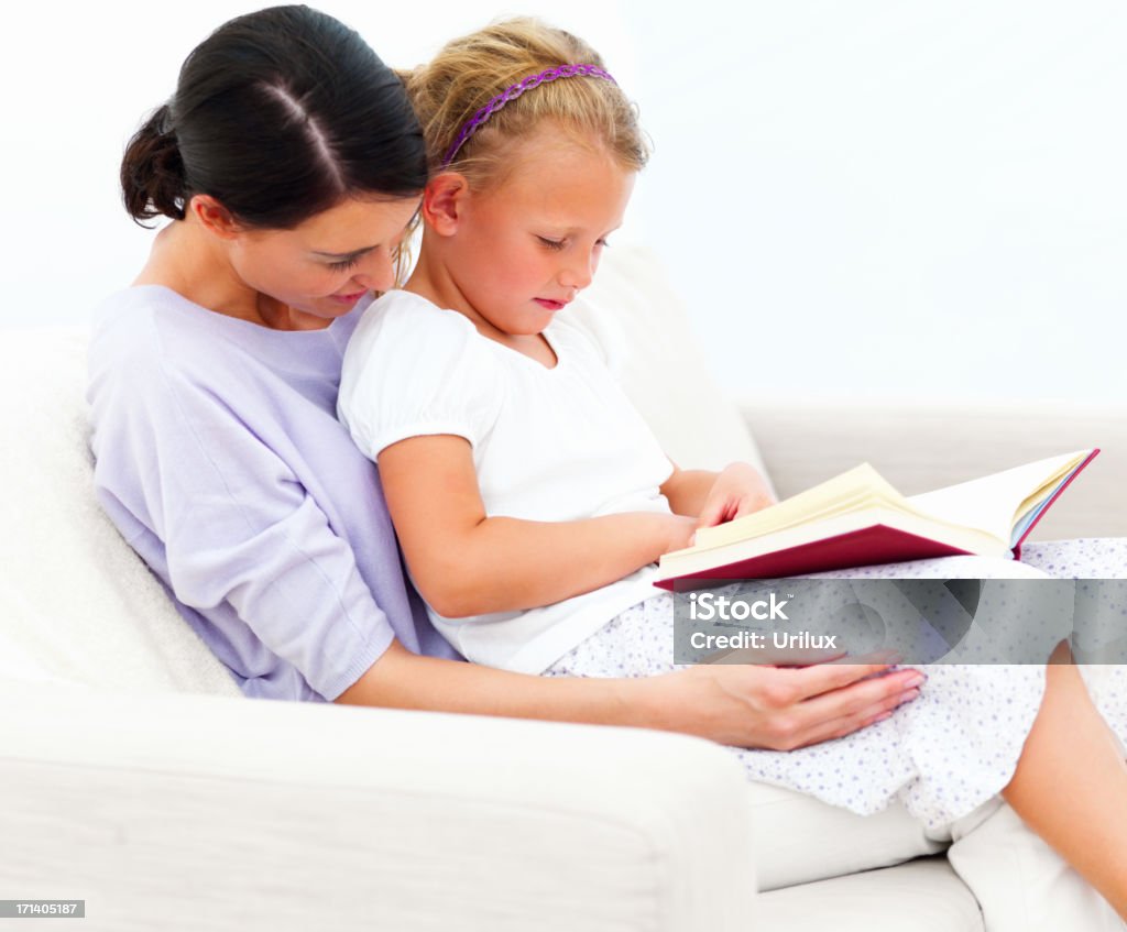 Mãe e filha sentada no sofá lendo livro e - Foto de stock de Adulto royalty-free