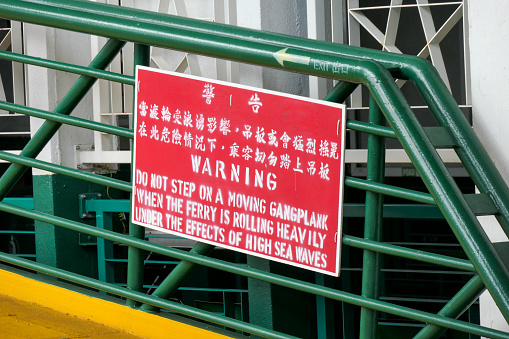 A warning sign on the gangplank exit of the Star Ferry terminal at Tsim Sha Tsui.   This image was taken on a hot and humid overcast afternoon on 4 July 2023.