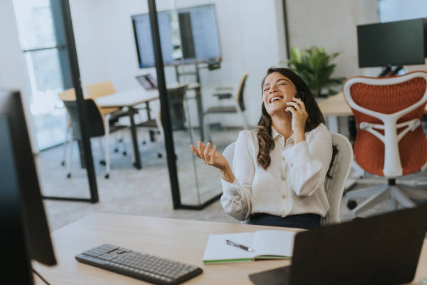 istock Young business woman using mobile phone while working on laptop in the modern office 1714090827