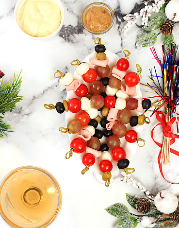 Christmas and New Year's dishes, a set of snacks and refreshing drinks for the festive table. A plate with canapes of tomatoes, mozzarella cheese, olives, black olives and grapes on a marble table, selective focus