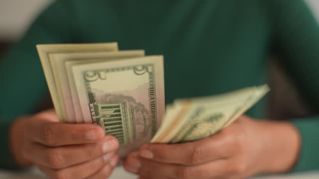 Close-up top view shot of unrecognizable African woman counting dollar bills. Closeup of black female hands count money cash at home. Concept of investment
