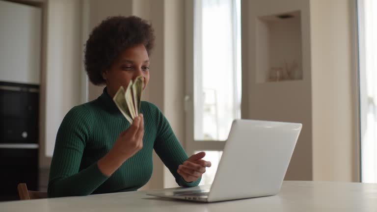 Happy cheerful African-American young woman showing on video call dollars cash won in lottery or casino. Concept of lending, success and winning.