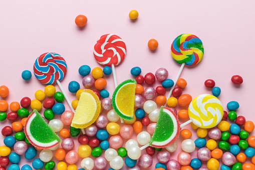 A large number of colorful candies on a pink background. The concept of sweets. Flat lay.