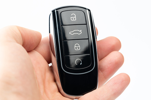 Modern black car key in palm hand macro close up view