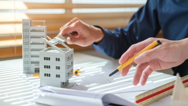 istock Close up architect hands working on a construction project and examining residential model at meeting. 1714172146