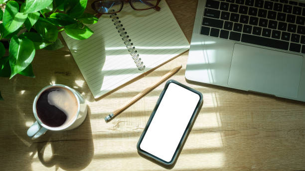 istock Mockup smart phone, laptop computer, notebook and coffee cup on wood table. Copy space. 1714178959