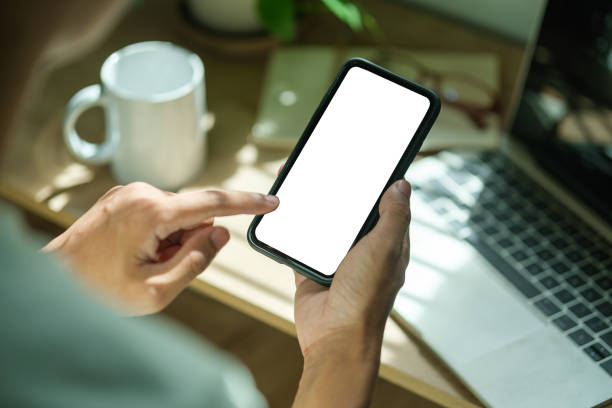 istock Over shoulder view of young man hands holding smart phone empty screen while sitting at workplace. 1714181123