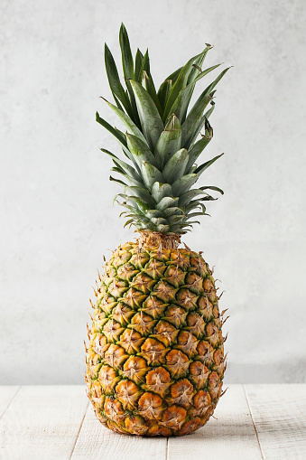 Juicy ripe pineapple on a light wooden background. The concept of harvesting, fruit, fruit market.