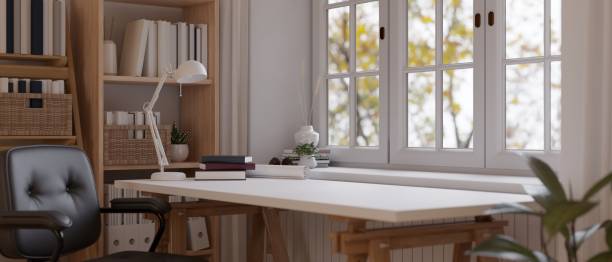 Minimal modern study room with large white wooden table against wall with windows and bookshelf.