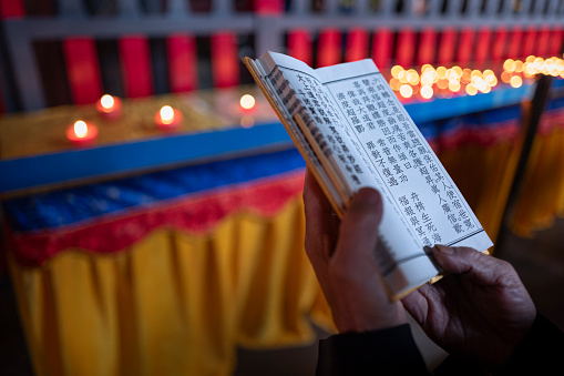 Taoist scriptures in the hands of a Taoist priest in a temple, Zixiao Palace in Wudang Mountain, China.