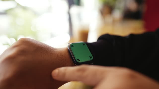 Man Touching And Swipping On Smart Watch With Green Screen While Taking A Break At Coffee Shop