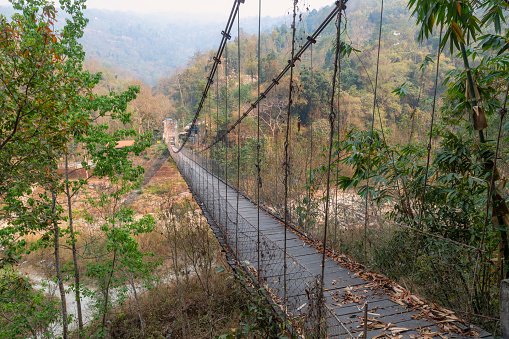 Suspension wooden bridge on Railey river surrounded by mountains and dense forest at Bidyang Valley in Kalimpong district of India