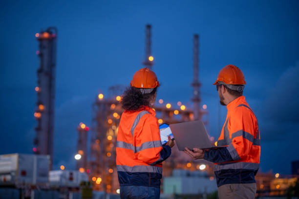 istock Engineers survey team wearing safety uniform and helmet under conversation document on hand and tablet inspect survey checking construction railway work station with oil refinery factory background 1714346796