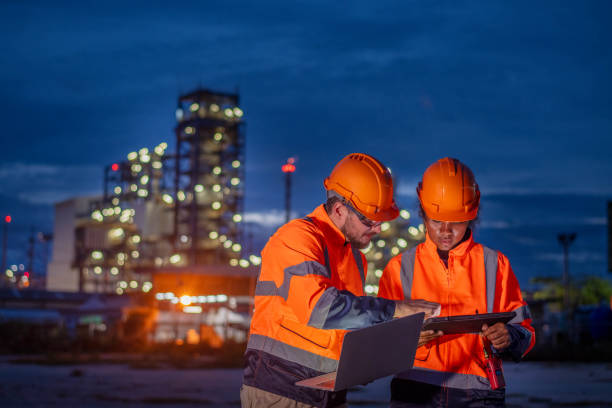 istock Engineers survey team wearing safety uniform and helmet under conversation document on hand and tablet inspect survey checking construction railway work station with oil refinery factory background 1714346800