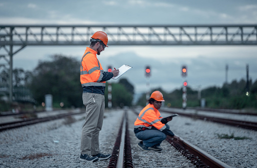 Engineer under discussion inspection and checking construction process railway switch and checking work on railroad station .Engineer wearing safety uniform and safety helmet in work.