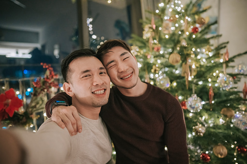 selfie Happy Asian Chinese gay couple in front of Christmas tree at night