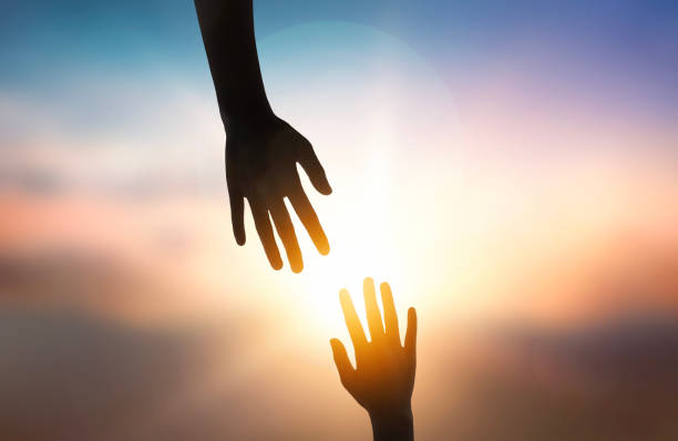 istock Silhouette of giving a helping hand over sunset background. 1714364016