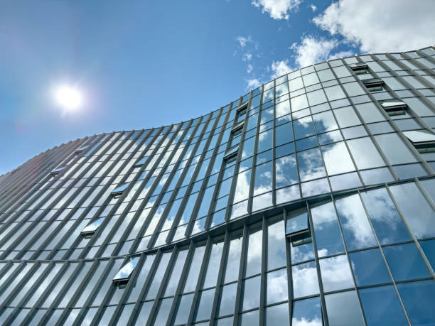 istock modern office building exterior. windows reflect the blue sky with clouds. 1714364838