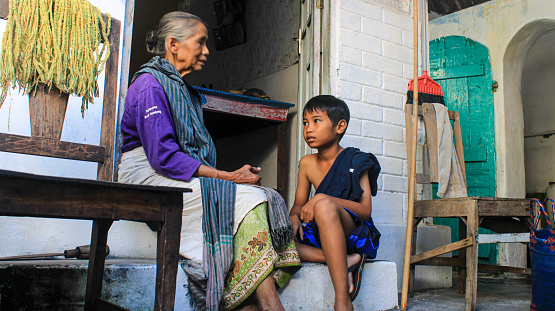 Yogyakarta, Indonesia. August, 12 2023. Grandmother chatting with her grandson at the door