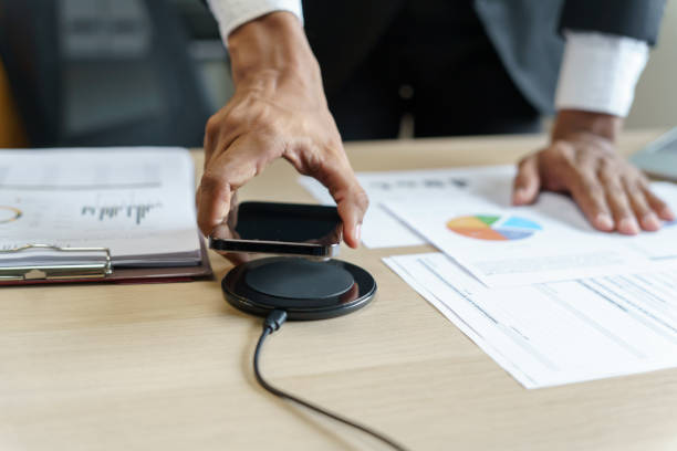 istock Charging mobile phone battery with wireless charging device in the table. Smartphone charging on a charging pad. Mobile phone near wireless charger Modern lifestyle technology concept 1714396690