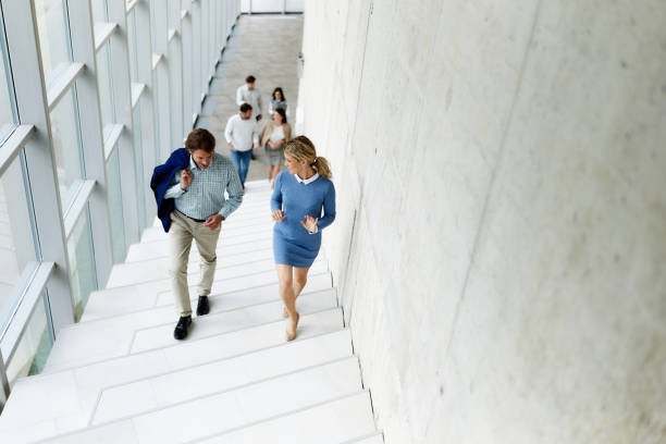 istock Happy business colleagues talking while walking up the stairs in a hallway. 1714472201