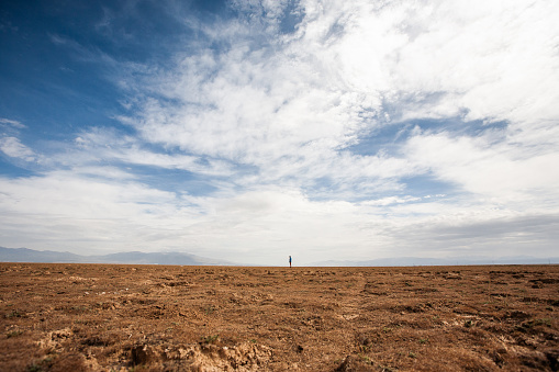 A man standing alone in an empty and flat field.
