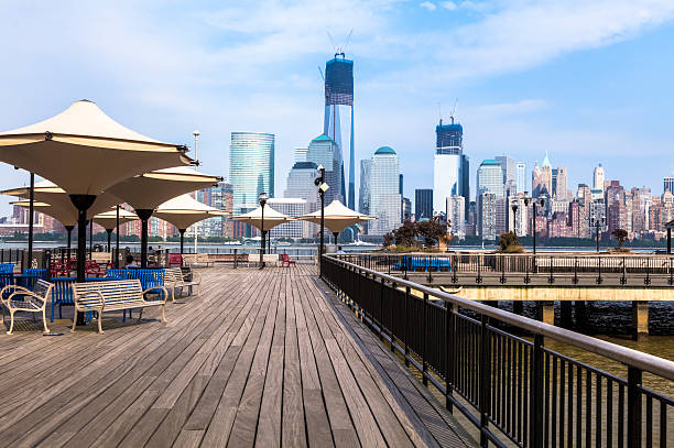 Boardwalk on Hudson River with Manhattan in background Lower Manhattan Skyline and the Hudson River Waterfront Walkway in Jersey City, New Jersey. jersey city stock pictures, royalty-free photos & images