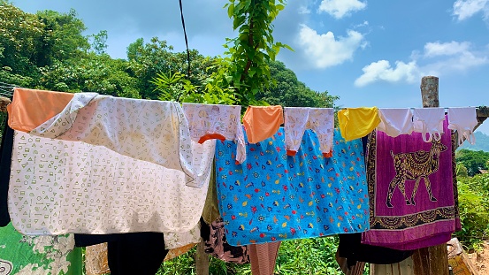 “Clothes Hanging on a Clothesline” depicts a visually appealing view of clothes hanging on a line, perfect for designs related to laundry services, clothing stores, or home decor.