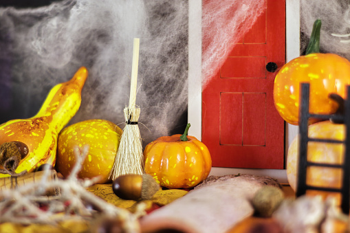 Spooky Halloween party decorations featuring a red door surrounded by cobwebs, pumpkins, and a mysterious broom, set against a dark background. Get ready for the Halloween festivities with this eerie scene. Perfect for your Halloween-themed projects and events.
