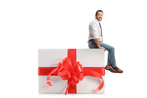 Professional man sitting on a big present box isolated on white background