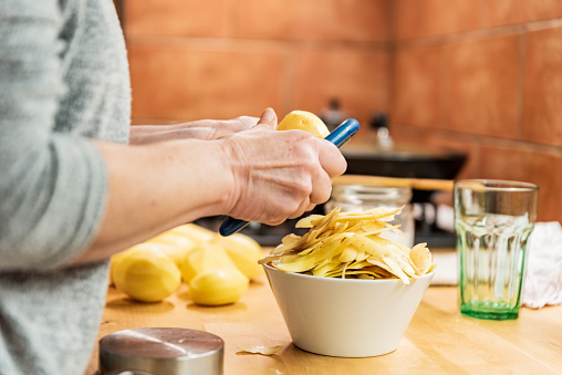 Woman in her Domestic Kitchen Peeling Potatoes for a Healthy Dinner