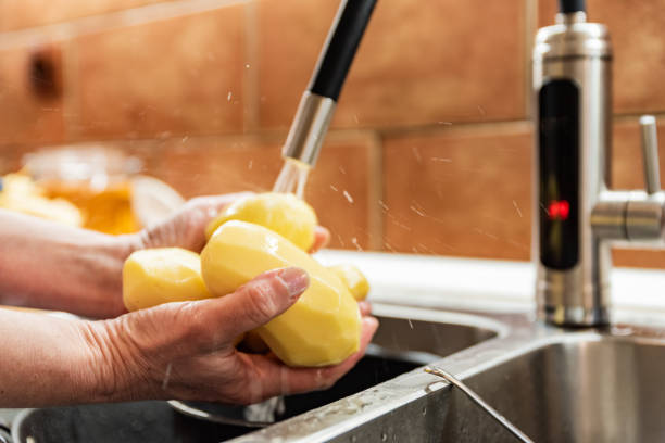 Woman in her Domestic Kitchen Washing Potatoes