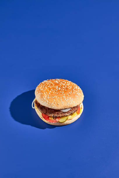 istock Beef burger blue background with hard shadow. American junk food minimal style. Hamburger trendy style.  Simple burger colour background. 1714576934