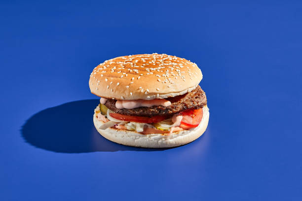 istock Beef burger blue background with hard shadow. American junk food minimal style. Hamburger trendy style.  Simple burger colour background. 1714576949