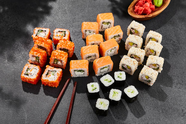 istock Maki sushi set on dark slate. Maki set with variety rolls. Composition from sushi rolls - philadelphia, california, hosomaki . Style concept sushi menu with black background, leaves and hard shadow. 1714577517