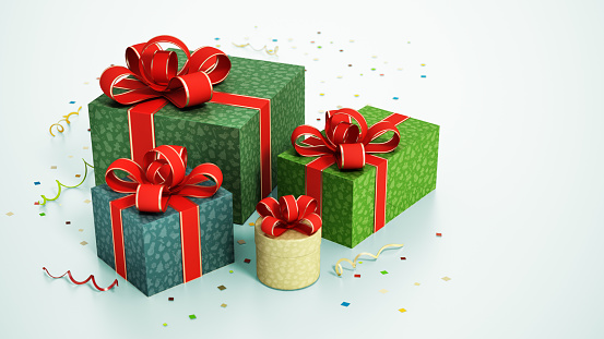 Group of Christmas giftboxes wrapped with red ribbons and confettis on light green background.