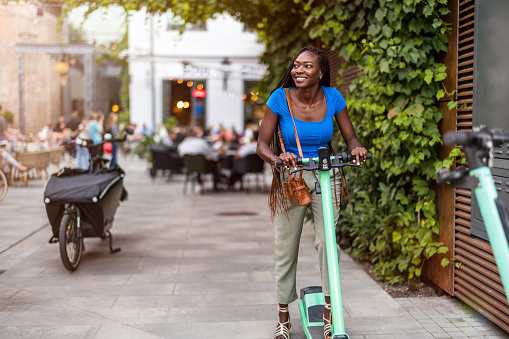 Portrait of a happy young woman riding an electric scooter in the city