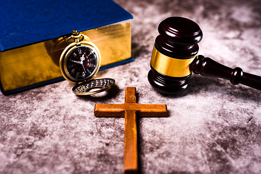 Bible, gavel, and Christian crucifix illustrate the judicial problems of the Catholic Church.